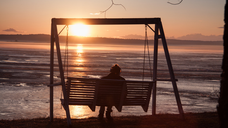Une femme sur un swing profitant du soleil de minuit en Finlande.