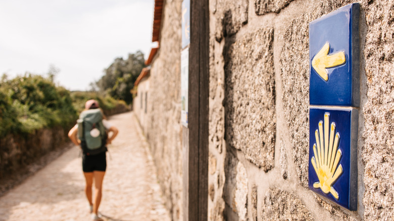 Randonneur marchant sur le Camino de Santiago avec un panneau pointant dans la direction