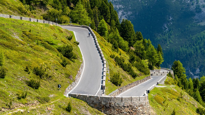 Un cycliste monte en haut de la passe de Stelvio par une journée d'été claire.