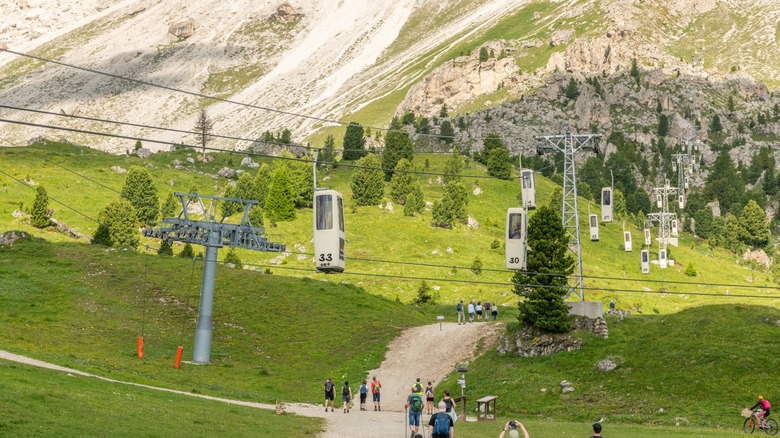 Les gondoles de cercueil font leurs boucles au-dessus de la vallée jusqu'à la montagne Sassolungo dans les Dolomites