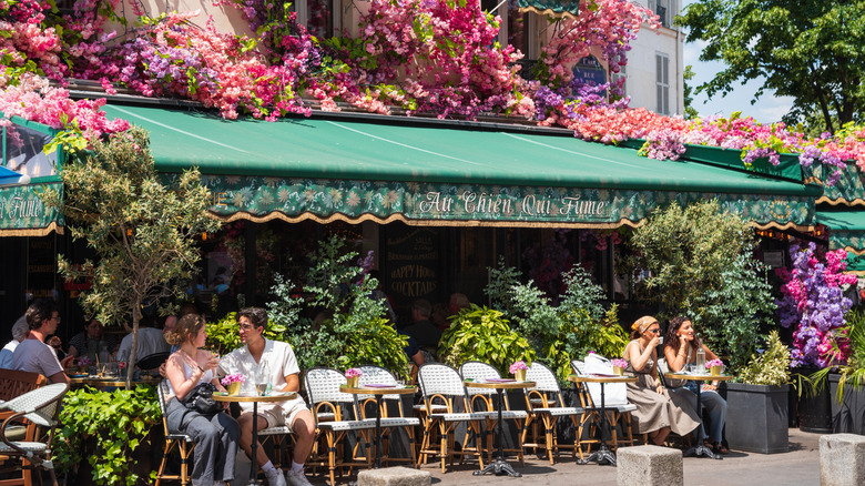 Un café français classique avec des sièges extérieurs de trottoir et une belle bougainvillea en fleurs