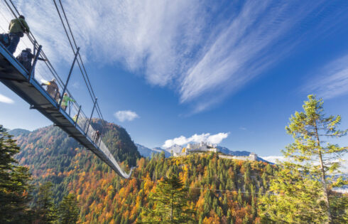 High dans les Alpes autrichiennes se trouve une ville pittoresque avec une passerelle vertigineuse de suspension à un château
