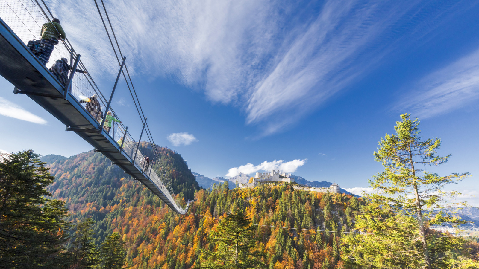 High dans les Alpes autrichiennes se trouve une ville pittoresque avec une passerelle vertigineuse de suspension à un château