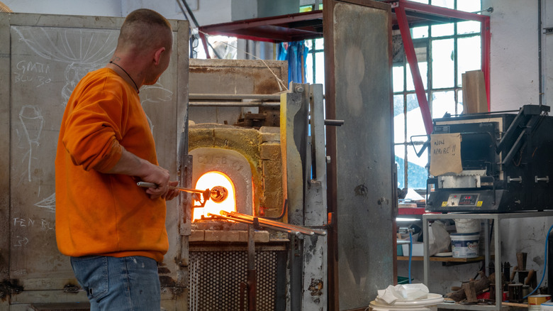 Un souffleur de verre façonne une pièce en verre dans un studio de verre traditionnel sur l'île de Murano, Venise,