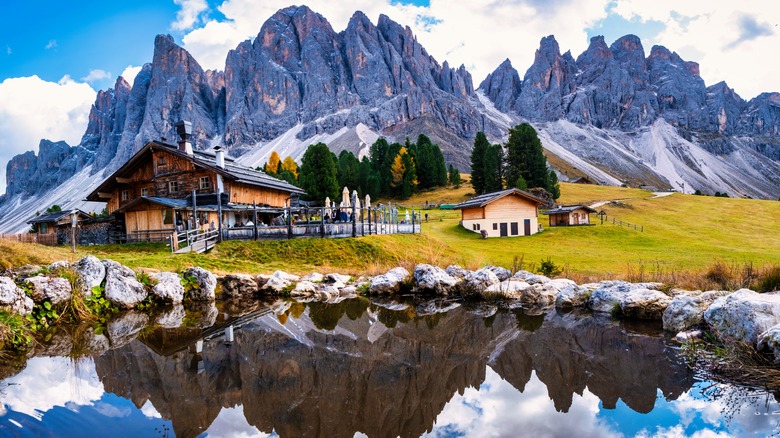 Vue de Geisleralm, une petite cabane alpine avec des montagnes et un étang entourant à Val di Funes, en Italie.