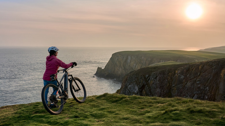 Un cycliste regardant le coucher du soleil au Mull de Galloway