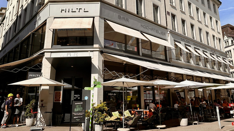 La façade de Hiltl avec des parapluies et des sièges en plein air, le plus ancien restaurant végétarien du monde.