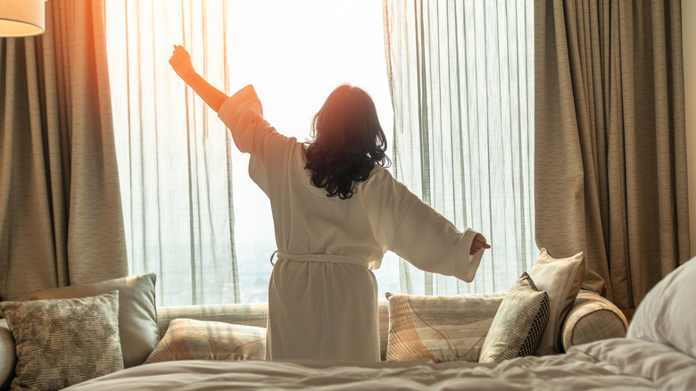 Femme se réveillant du bon sommeil sur le lit de l'hôtel et s'étire
