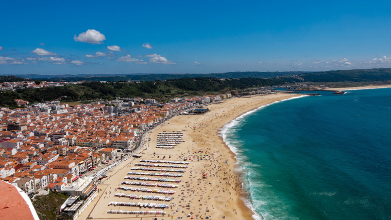 Vue aérienne d'un village balnéaire avec des bâtiments à toit rouge, Nazaré