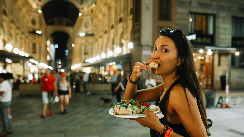 Une femme mangeant de la pizza à Milan