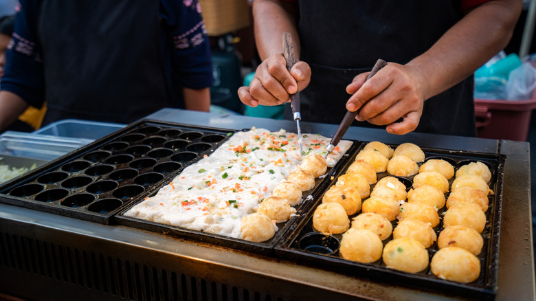 Chef cuisinant le célèbre Takoyaki d'Osaka sur une poêle chaude