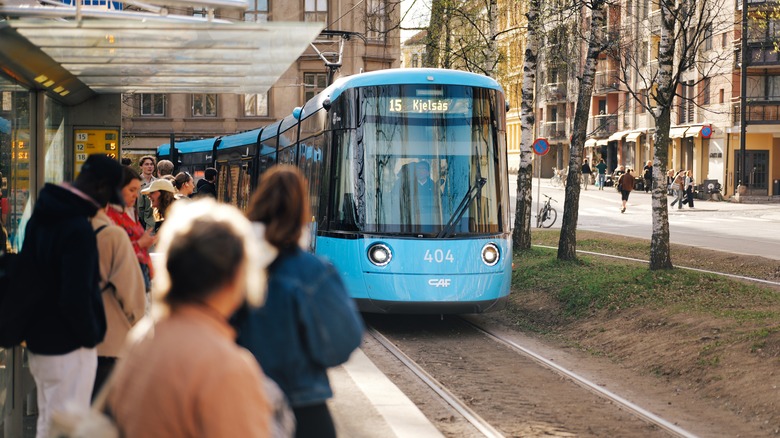Un tramway bleu s'approchant d'une station bondée à Oslo