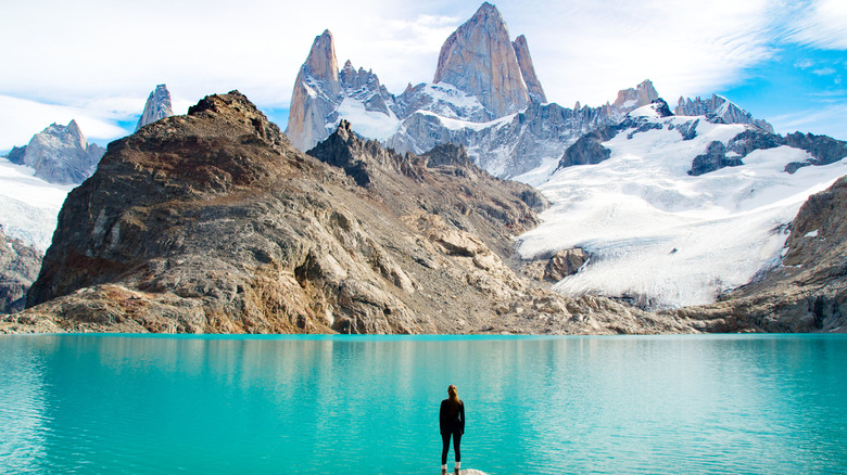 Randonneur debout devant le lac glaciaire surplombant les falaises de montagne imposantes en Patagonie