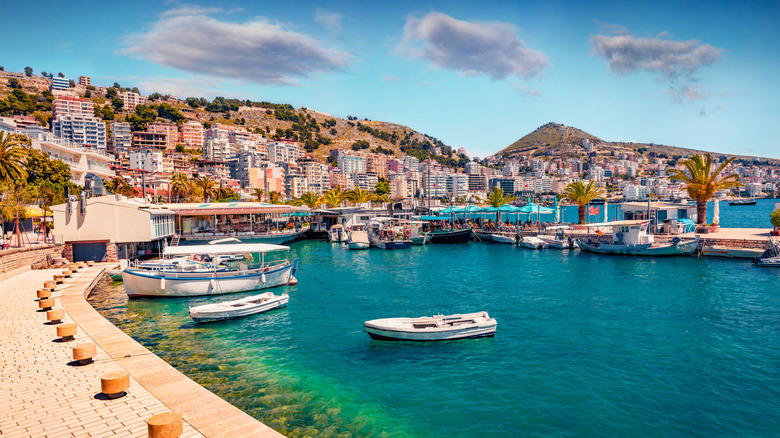 Ville côtière de Saranda, avec des bateaux amarrés sur les eaux bleues et des bâtiments sur les collines en arrière-plan