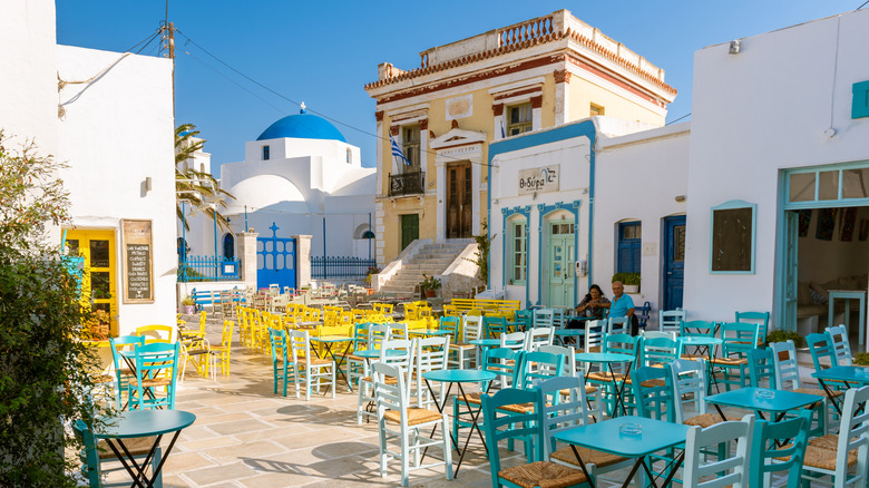 Tables et chaises colorées avec des bâtiments blanchis à la chaux sur la place de la ville d'Hora à Serifos, Grèce