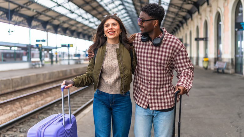 Couple poussant des valises le long d’un quai de gare