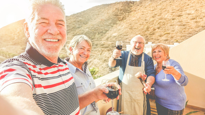 Un groupe de personnes âgées mangeant et buvant du vin sur fond de montagne