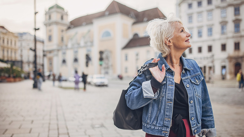 Femme plus âgée seule dans les rues de Vienne regardant les grands bâtiments en pierre de grès qui l'entourent