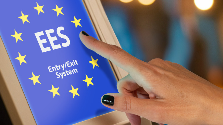 Gros plan d'une main pressant celle de l'Europe "Système d'entrée/existence" écran tactile à l'aéroport