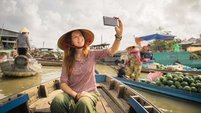 Femme touriste prenant un selfie à bord d'un bateau de marché flottant