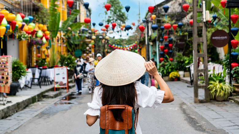 Vue arrière du touriste asiatique portant un chapeau traditionnel vietnamien