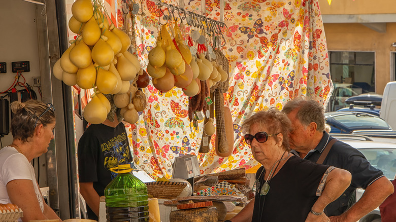 Les habitants âgés se rassemblent sur un stand de fromage et de jambon à Arzachena, en Sardaigne