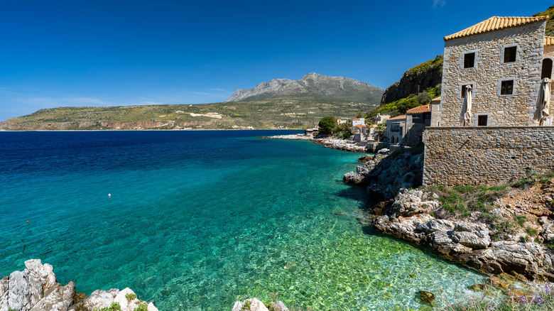 Maisons de bord de mer donnant sur une mer céruléenne avec des montagnes en arrière-plan à Limeni, Grèce