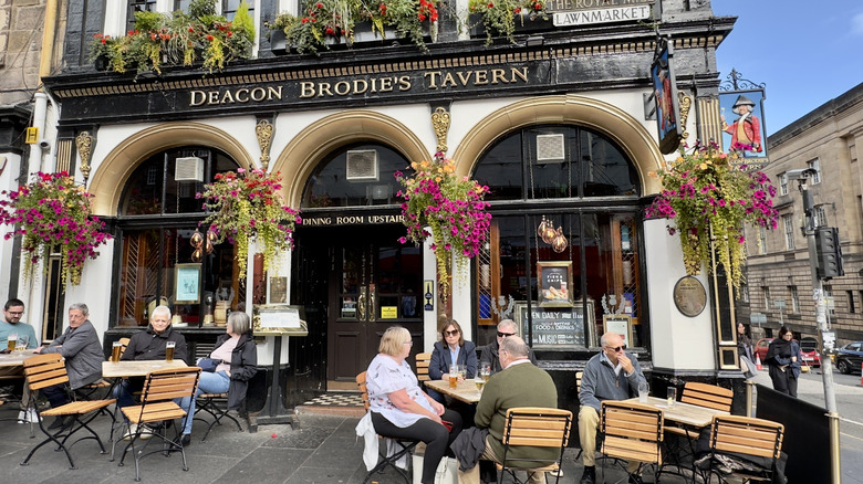 Touristes assis sur la terrasse devant la taverne du diacre Brodie en Écosse