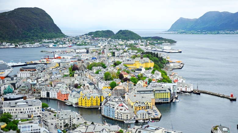 Vue aérienne d'une ville côtière avec des bâtiments colorés, entourée de collines verdoyantes, Ålesund, Norvège