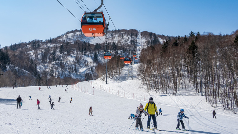 Skieurs sur une montagne avec des télécabines de ski rouges au-dessus