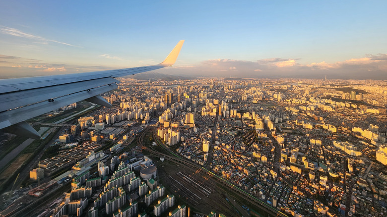 Une vue de Séoul depuis la fenêtre d'un avion pendant l'heure d'or, avec une aile d'avion au premier plan