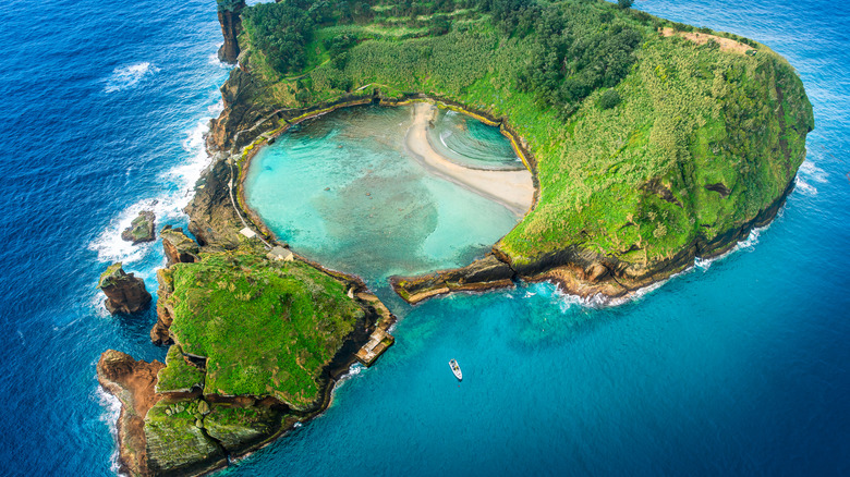 Vue plongeante sur une île volcanique abritant une piscine naturelle et entourée par la mer