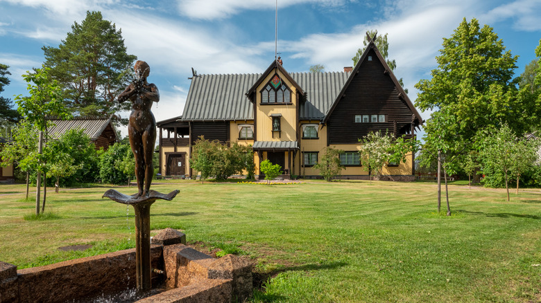 Maison d'artiste et jardins avec statue par une journée ensoleillée