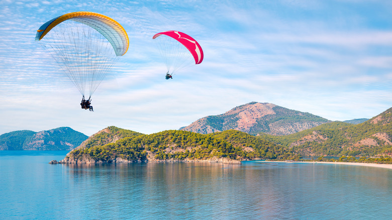 Parapentes dans les airs au-dessus de l'eau avec des montagnes