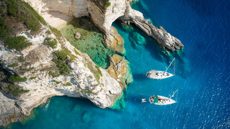Image vue de dessus de deux voiliers amarrés à côté de falaises blanches et de leurs baies naturellement formées.