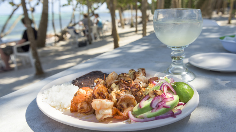 Une assiette de plats mexicains avec une margarita et une plage en arrière-plan à Tulum, Mexique