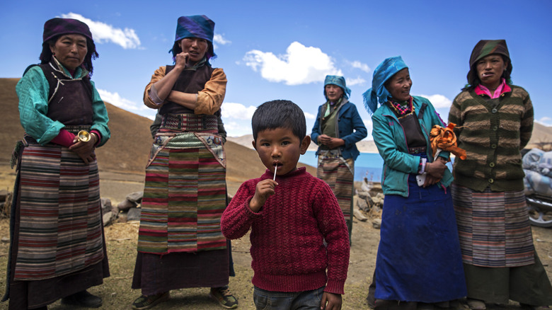 Un groupe de femmes et un enfant devant un lac au Tibet