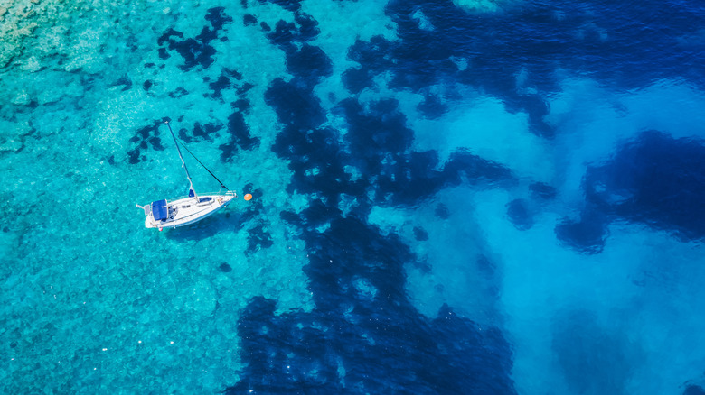 Un bateau flotte dans la mer bleue juste à côté de la plage de Fteri, à Céphalonie