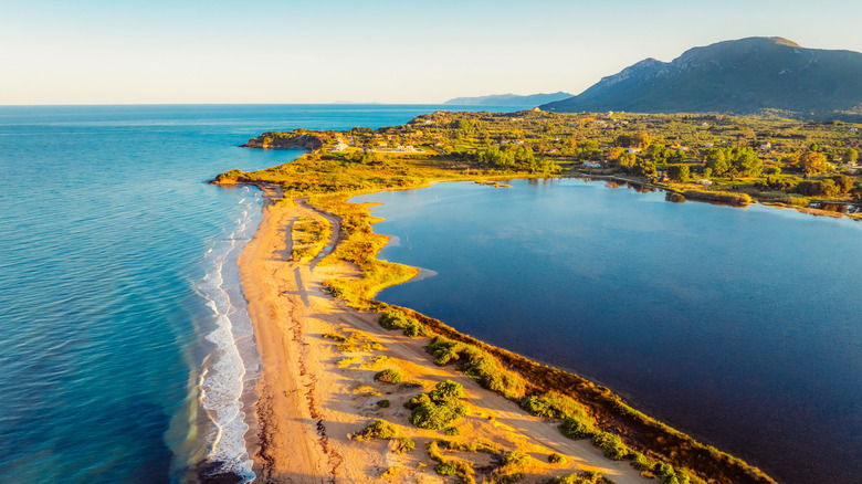 Halikounas Beach Corfou sable éclairé par le soleil doré avec des vagues s'écrasant sur le rivage et encore le lac