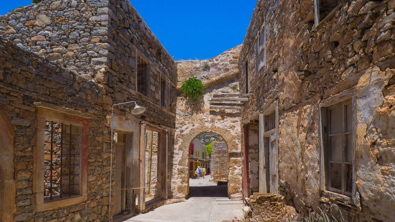 Une rue mince sur Spinalonga avec des bâtiments en brique abandonnés et une petite arcade