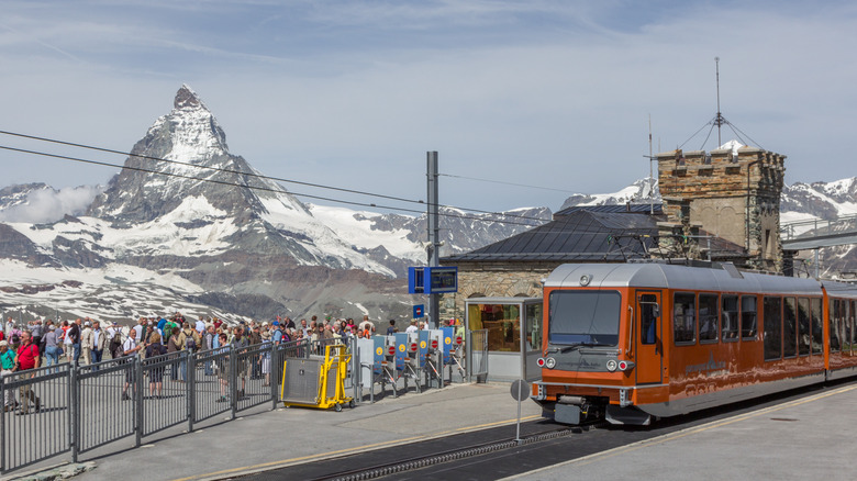 Touristes dans une gare en Suisse avec le Cervin en arrière-plan