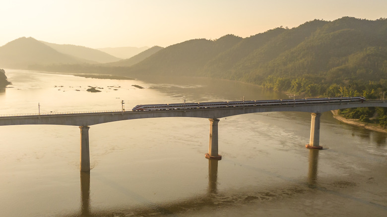 Un train ferroviaire Laos-Chine traversant le fleuve Mékong sur un pont ferroviaire.