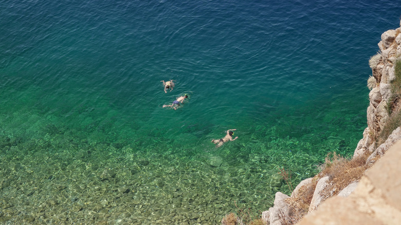 Vue depuis la falaise de la magnifique eau claire d'Hydra, en Grèce, avec plusieurs nageurs