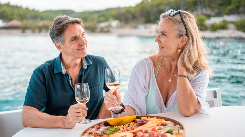 Un couple de retraités souriant sirotant du vin blanc et prenant un repas au bord de l'eau en Croatie