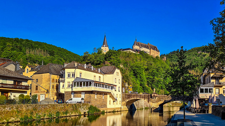 Le village de Vianden au Luxembourg, vu de la rivière Our en regardant le château sur la colline au-dessus de la ville.
