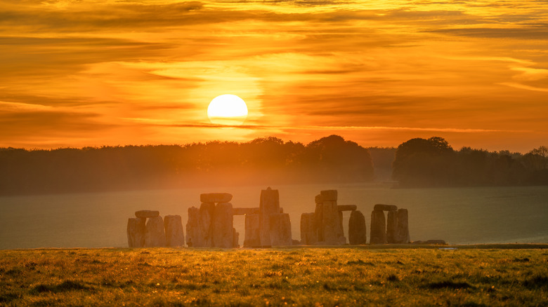 Lever de soleil au-dessus de Stonehenge au milieu d'un paysage brumeux
