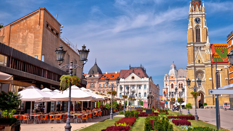 Une rue pittoresque de Novi Sad, en Serbie, avec des cafés en plein air et une cathédrale au loin