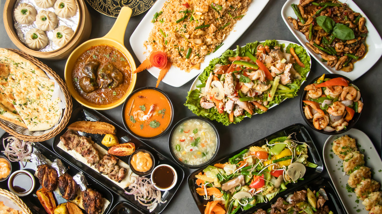 Vue de haut en bas d'une grande variété de plats du sud de l'Inde sur une table, notamment du mouton masala, du poulet karahi, du naan à l'ail, etc.